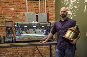 Pete Licata stands in the Parisi Coffee roasting plant with his world championship trophy. Photo by Julia Larberg