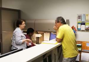 Office Coordinator Rebeh Ghadiri (from left)) and Nirmal Samuel, student assistant, help international student Nirmal Samuel with his documentation needs. Photo by Lance Martin