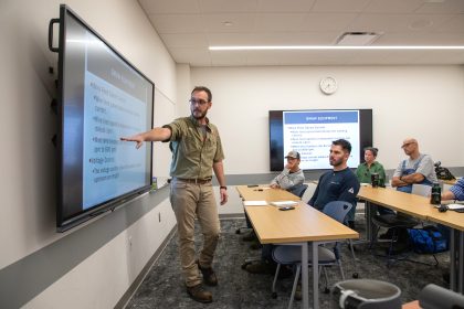instructor standing in classroom pointing at monitor